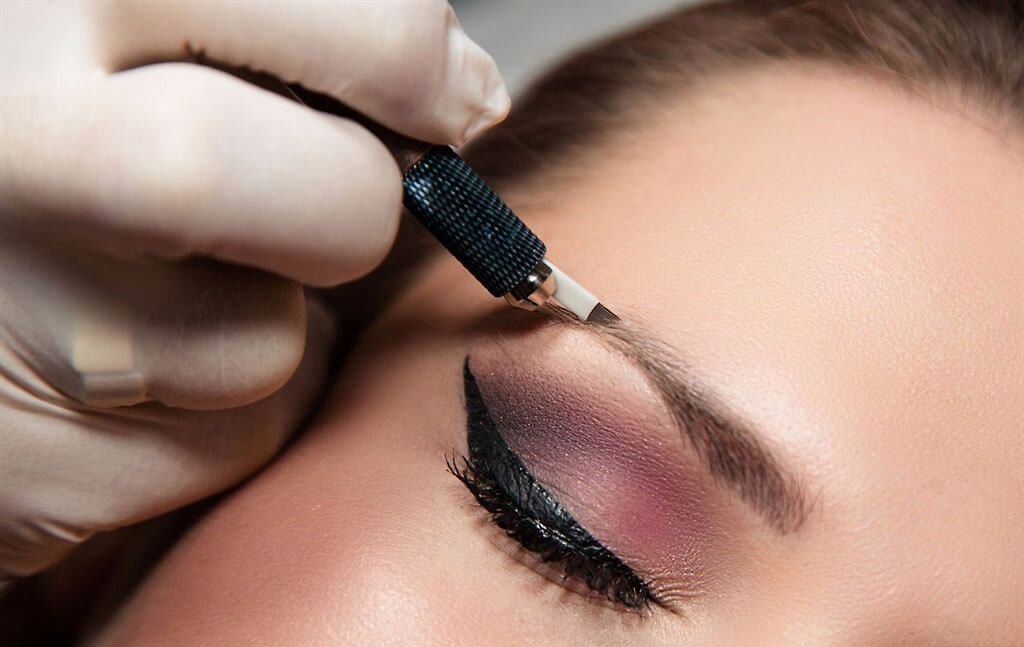 Photo of microblading artist using microblading hand tool to create hairline strokes in eyebrow