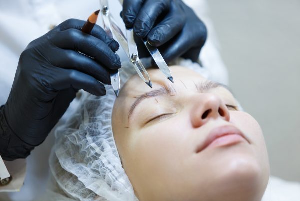 Microblading eyebow artist mapping client eyebrows to determine best brow shape face